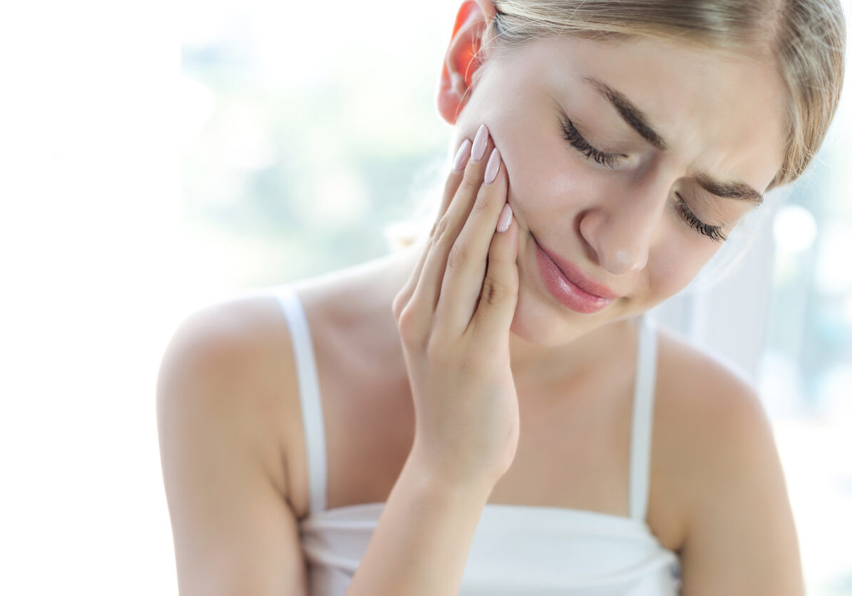 Teen girl holding side of face, indicating tooth pain